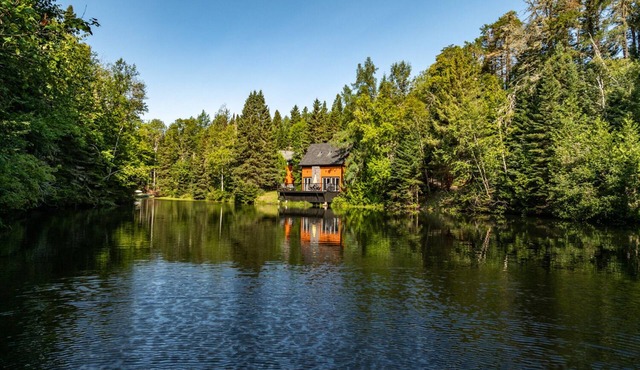 Cottage on the edge of a lake with trail, waterfall and pond